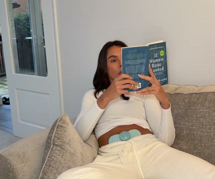 Woman reading on the sofa wearing Myoovi on her belly